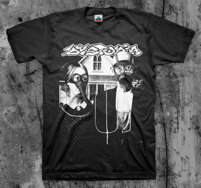 Puede incluir: Camiseta negra con un gr&aacute;fico en blanco y negro de una pareja con m&aacute;scaras de gas frente a una casa. La palabra "Dyslexia" est&aacute; impresa encima de la pareja en una fuente estilizada.