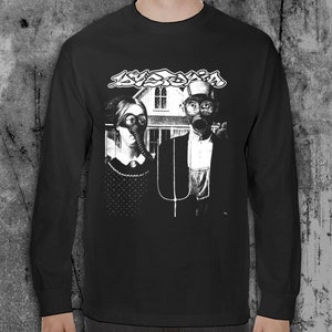 Puede incluir: Camiseta negra de manga larga con un gr&aacute;fico en blanco y negro. El gr&aacute;fico muestra dos figuras con m&aacute;scaras de gas frente a una casa, con la palabra "AVOXIA" encima. La camiseta es de material suave.