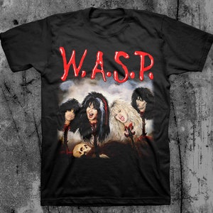 May include: Black t-shirt with a graphic print of the band W.A.S.P. The band members are depicted with their heads cut off and blood dripping from their necks. The band's name is written in red letters above the image.