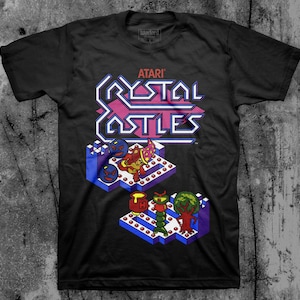 May include: Black t-shirt featuring the Atari Crystal Castles arcade game logo and graphics. The design includes the game's title in a pink and white font, along with pixelated characters and level elements.