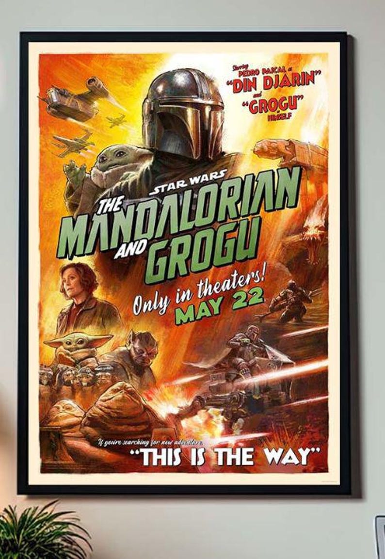 May include: A framed movie poster for "The Mandalorian and Grogu" featuring Din Djarin and Grogu. The poster has a vintage style with a yellow and orange background, and the text "This is the Way".