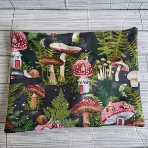 May include: A rectangular pillowcase featuring a whimsical forest scene. The design includes various mushrooms, some with house-like structures, ferns, snails, and crescent moons. The color palette is dominated by dark green, red, brown, and white.