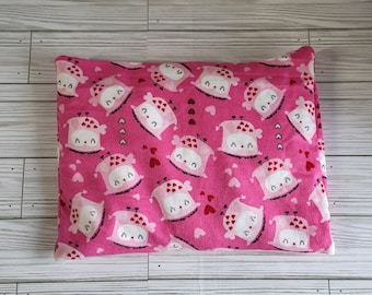 Op de afbeelding: Een rechthoekig roze kussen met een herhaald patroon van cartoonuilen en hartvormige accenten. De uilen hebben witte gezichten, roze lichamen en rode hartdetails. De achtergrond is effen roze.