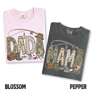 May include: Two Comfort Colors t-shirts, one blossom pink and one pepper gray, feature fishing-themed graphics. The word "DADA" is on the pink shirt, and "MAMA" is on the gray shirt. Each graphic includes a fishing rod, hat, and fishing-related illustrations.