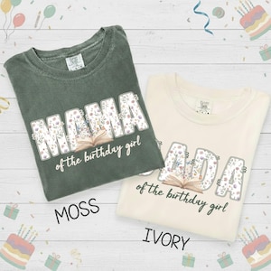 May include: Two t-shirts, one moss green and one ivory, with the word "MAMA" and "ADA" in floral print. Below the words is an open book graphic and the text "of the birthday girl".