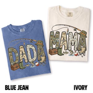 May include: Two t-shirts, one blue and one ivory, with fishing-themed designs. The blue shirt says "DADA" and the ivory shirt says "MAMA", both with fishing rod graphics and fishing-related illustrations within the letters.