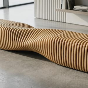 Può includere: Una panca lunga costruita con una serie di listelli di legno chiaro disposti verticalmente. La panca presenta una forma ondulata distinta che si curva verso l'interno al centro, creando un motivo ritmico e continuo di legno.