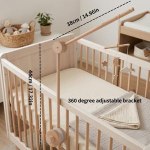 May include: A wooden baby crib mobile with a 360-degree adjustable bracket. The mobile arm is 38cm/14.96in long and the vertical support is 44cm/17.32in. The mobile features wooden stars, moons, and clouds.