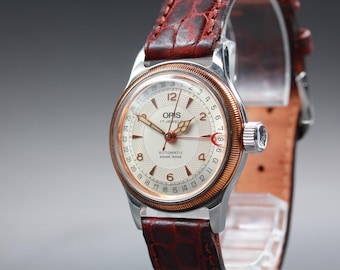 Reloj ORIS automático con puntero y fecha, tono oro rosa, bisel con borde estriado, 32 mm, para hombre.