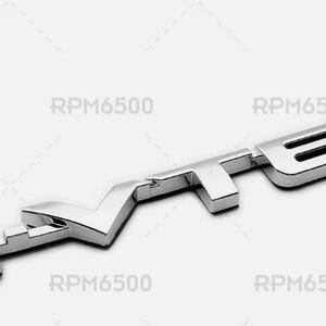 May include: A chrome-finished emblem with the word "TEC" in a stylized font. The emblem is angled slightly, with the letters connected and raised from the surface. The background is plain white.