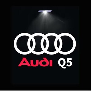 May include: Black background with the Audi logo, four interlocking white rings, and the red text "Audi Q5". A spotlight shines from above.