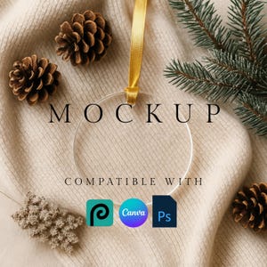 Peut inclure: Un ornement en verre transparent avec un ruban doré, entouré de pommes de pin et de brins de conifères. Le mot "MOCKUP" est affiché au-dessus de l'ornement, avec "COMPATIBLE AVEC" et des logos de logiciels en dessous. Le fond est un tissu tricoté crème.