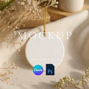 May include: A white, round ceramic ornament with a gold string for hanging. The word "MOCKUP" is printed across the top, with "COMPATIBLE WITH" and Canva and Ps logos below. The ornament is set against a neutral, textured background.