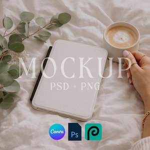 Puede incluir: Una funda blanca para tableta con la palabra "MOCKUP" y "PSD + PNG" impresas. Una taza de café con arte latte es sostenida por una mano con anillos dorados. También se ven ramas de eucalipto y logotipos de software de diseño.