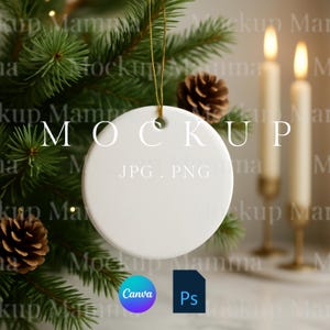 May include: A white, round ceramic ornament with a gold string, hanging in front of a Christmas tree. The word "MOCKUP" is printed on the ornament. The image also includes pine cones, candles, and the Canva and Photoshop logos.