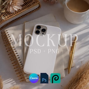 May include: A white smartphone case with a triple-lens camera is the focal point of this image. The phone rests on a stack of notebooks, with a gold pen, a cup of coffee, and a woven basket in the background. The word "MOCKUP" is printed on the phone.