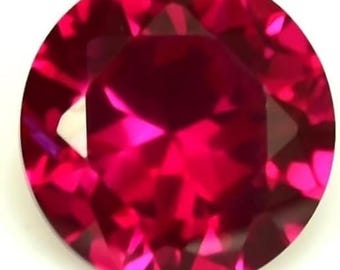 May include: A round, faceted ruby gemstone. The gem is a deep, vibrant red color with multiple facets that reflect light. The gemstone is set against a white background.