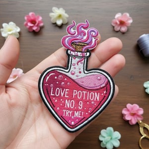 Puede incluir: Parche bordado con forma de botella de poción en forma de corazón. La botella está llena de líquido rosa y tiene el texto "LOVE POTION NO. 9 TRY ME!". El parche tiene un borde blanco y llamas rosas y moradas.