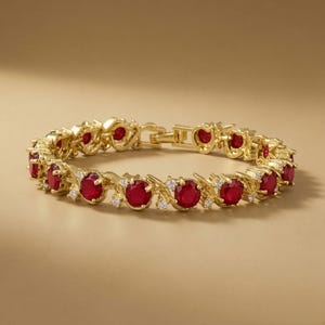 May include: A gold-toned bracelet featuring a series of round, deep red stones alternating with smaller, clear white stones. The metal links are arranged in a continuous, articulated pattern with a secure clasp mechanism visible at the top.