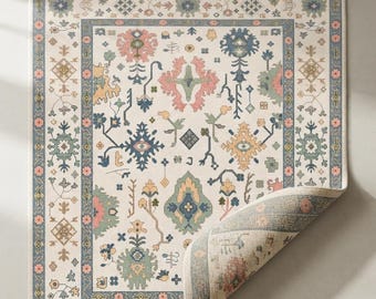 May include: A rectangular area rug with a cream-colored base featuring a repeating pattern of floral and geometric motifs in muted shades of blue, pink, green, and yellow. The rug has a blue border with small pink flowers and a fringed edge.