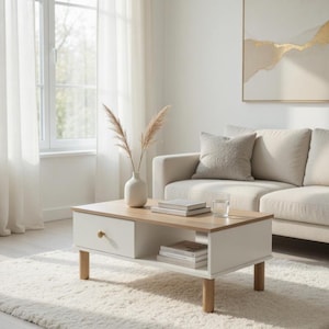 Könnte beinhalten: Ein moderner Couchtisch mit weißem Sockel und einer Oberseite aus Naturholz. Er hat eine Schublade mit einem runden Holzknauf und ein unteres Regal. Eine Vase mit getrockneten Pflanzen und Bücher stehen auf dem Tisch. Der Tisch ist 102 cm lang.