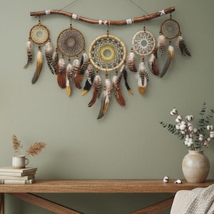 May include: A handcrafted dreamcatcher with multiple circular woven webs, adorned with feathers in shades of brown, yellow, and white. The dreamcatcher is suspended from a wooden branch, creating a bohemian wall decor piece.