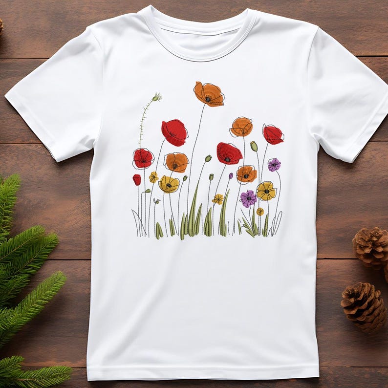 May include: White t-shirt featuring a colorful floral design. The graphic includes red, orange, yellow, and purple flowers with green stems and leaves. The flowers are stylized with black outlines, creating a whimsical and artistic look.