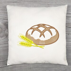 Peut inclure: Coussin carr&eacute; blanc avec un motif brod&eacute; d'un pain et de deux &eacute;pis de bl&eacute;. Le pain est marron avec un motif quadrill&eacute; et le bl&eacute; est jaune.