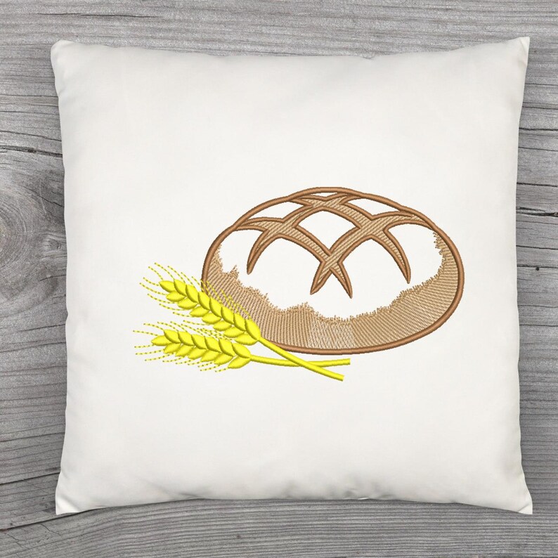 Peut inclure: Coussin carr&eacute; blanc avec un motif brod&eacute; d'un pain et de deux &eacute;pis de bl&eacute;. Le pain est marron avec un motif quadrill&eacute; et le bl&eacute; est jaune.