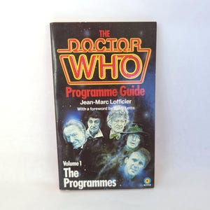 May include: A vintage "Doctor Who" Programme Guide, Volume 1, with the show's logo in red and yellow. The cover features images of actors and the text "The Programmes". A collectible book for fans of the classic series.