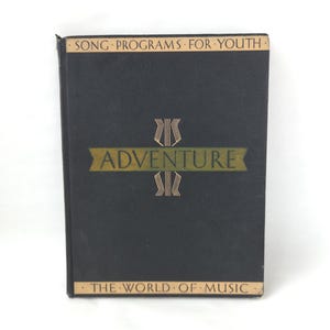 May include: A vintage book with a black cover and gold lettering. The title "Adventure" is displayed prominently, with the text "Song Programs For Youth" and "The World of Music" above and below. The book has a decorative design.