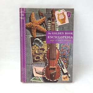 May include: A vintage hardcover book titled "The Golden Book Encyclopedia, Book 14: Silk to Textiles." The cover features illustrations of a starfish, musical instruments, a spacecraft, and a stained-glass window. The spine is purple.