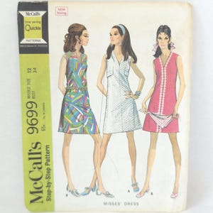 May include: A vintage McCall's 9699 sewing pattern envelope for a sleeveless dress. The cover features illustrations of three variations of the dress: one with a colorful geometric print, one in white, and one in solid pink with white trim.
