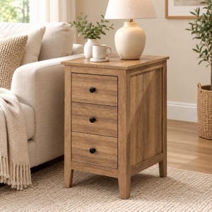 May include: A light brown wooden end table featuring three stacked drawers with small black circular knobs. The rectangular table has four straight legs and a smooth top surface, providing a compact storage solution for a living space.