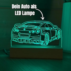 Könnte beinhalten: Eine neongrüne LED-Lampe in Form eines Sportwagens, die auf einem Holzsockel steht. Der Umriss des Autos ist beleuchtet, mit dem Text "Dein Auto als LED Lampe" darüber. Das Design ist modern und stilvoll.