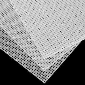 May include: Close-up of several white plastic canvas sheets. The sheets are layered, revealing a grid of square holes. The material appears to be translucent, with a matte finish. The background is black.