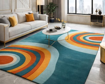 May include: A large, rectangular area rug with a vibrant, retro design. The rug features a teal background with curved, concentric bands of orange, yellow, and light blue. The rug is placed in a living room with a white sofa and gold accents.