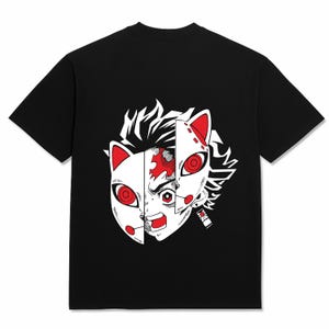 May include: Black t-shirt featuring a graphic design of a split face with red and white accents. The design includes a cat-like mask and a character's face, with red eyes and a determined expression. The shirt is made of a soft material.