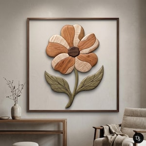 May include: A wooden flower wall art piece. The flower has brown, light brown, and tan petals, a dark brown center, green leaves, and a brown stem. The artwork is framed in a dark brown wooden frame and mounted on a light beige background.
