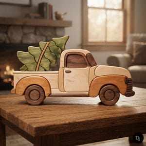 May include: A handcrafted wooden toy truck featuring a light-colored cab and bed, darker brown fenders and wheels, and a dark wood window frame. A large, stylized green wooden Christmas tree is secured in the truck bed, angled toward the rear.