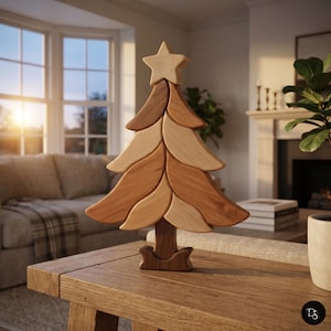 Peut inclure: Une sculpture décorative de sapin de Noël en bois présentant un design superposé aux tons multiples avec des segments de bois brun clair et moyen. L'arbre est surmonté d'une étoile à cinq branches et repose sur une base incurvée et robuste.