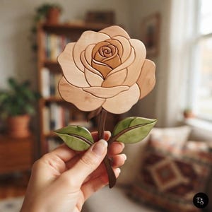May include: A handcrafted wooden rose sculpture featuring layered, light-toned petals forming a blooming flower head, attached to a dark brown stem with two smooth, light green leaves. The piece displays natural wood grain textures throughout.