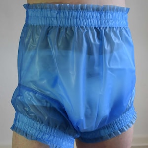 Könnte beinhalten: Hellblaue Plastikshorts mit elastischem Bund und Beinöffnungen. Die Shorts haben eine Rüschenborte an Taille und Beinöffnungen. Das Material scheint durchscheinend zu sein.