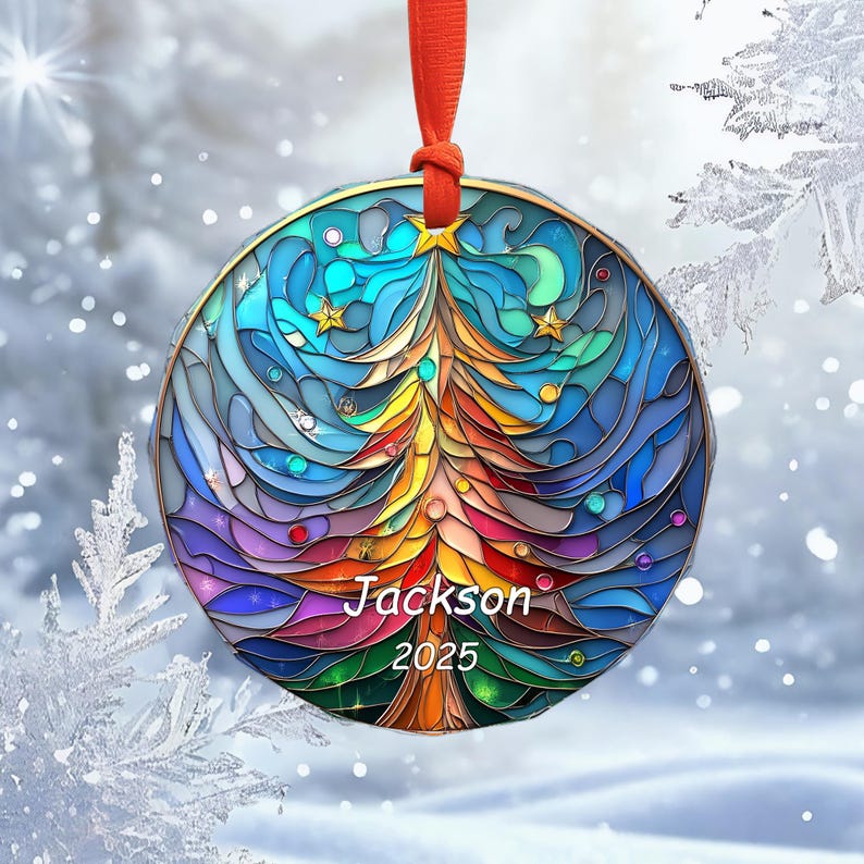 May include: A round Christmas ornament with a stained-glass design. The ornament features a colorful Christmas tree in the center, with the name "Jackson" and the year "2025" below. The ornament is trimmed in gold and has a red ribbon for hanging.