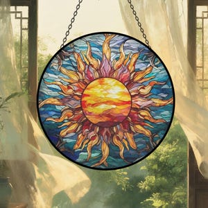 May include: A round stained glass suncatcher with a black border. The sun design features a yellow and orange center with radiating orange and red flames against a blue background. It hangs from a chain.