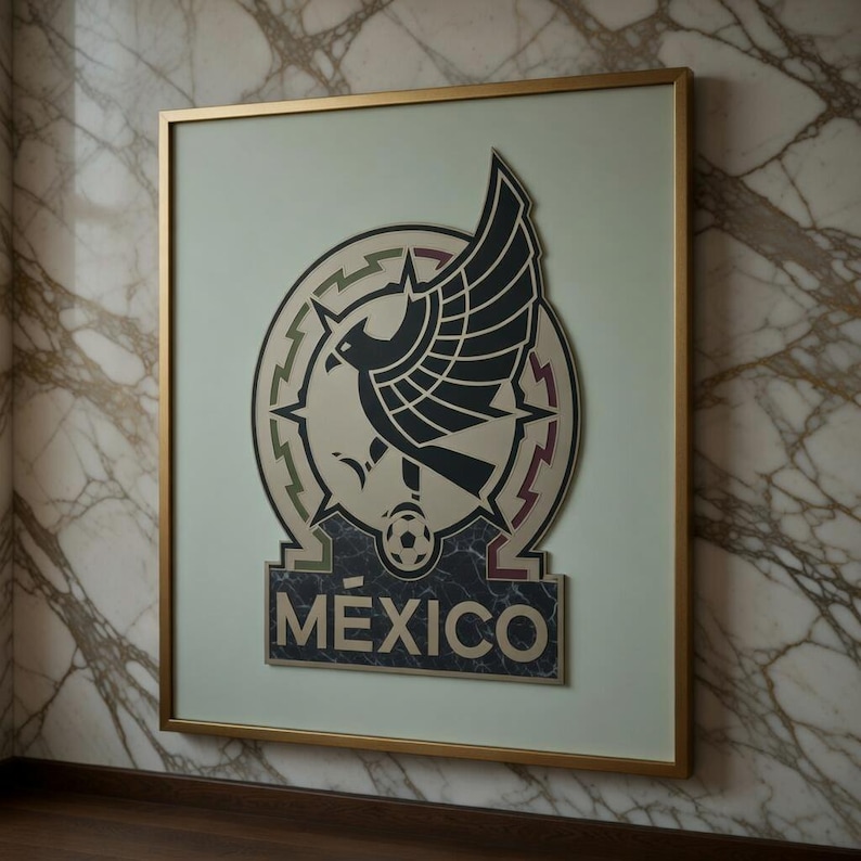 May include: Framed artwork featuring the Mexican national team emblem. The emblem includes a stylized eagle with outstretched wings, a soccer ball, and the word "M&Eacute;XICO" in a dark marble-like rectangle. The frame is gold-colored.