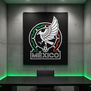 May include: A framed black poster featuring the Mexico national team emblem. The emblem includes a white eagle with outstretched wings, a soccer ball, and the word "M&Eacute;XICO" in white. The poster hangs on a gray concrete wall above a black desk.