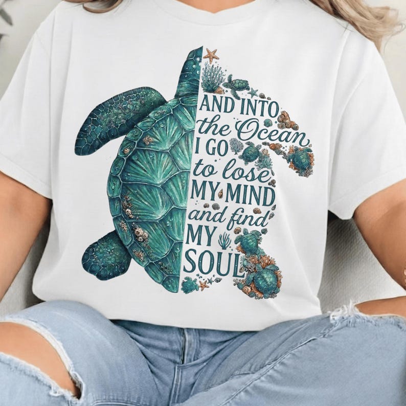 May include: White t-shirt featuring a teal sea turtle design. The turtle is split, with one side a detailed illustration and the other side containing the text "AND INTO the Ocean I GO to lose MY MIND and find MY SOUL."