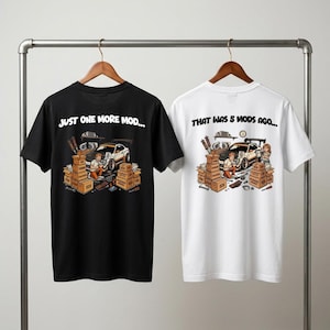 Puede incluir: Dos camisetas, una negra y otra blanca, con gráficos de coches. La camiseta negra dice "JUST ONE MORE MOD..." y la blanca "THAT WAS 5 MODS AGO...". Cada diseño muestra un coche con cajas y herramientas.