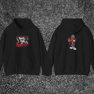Peut inclure: Sweat-shirt à capuche noir avec un motif de voiture de sport rouge et le texte "Street King" à l'avant. Le dos présente un personnage de dessin animé rouge et blanc. Le sweat-shirt est en matière douce.